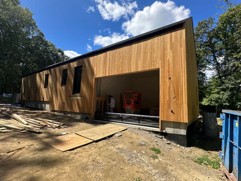 Modern cedar building with large garage opening under construction